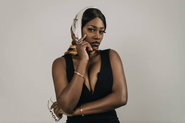 Portrait of a beautiful young black woman wearing an elegant black dress and headscarf, studio shot in front of a white background