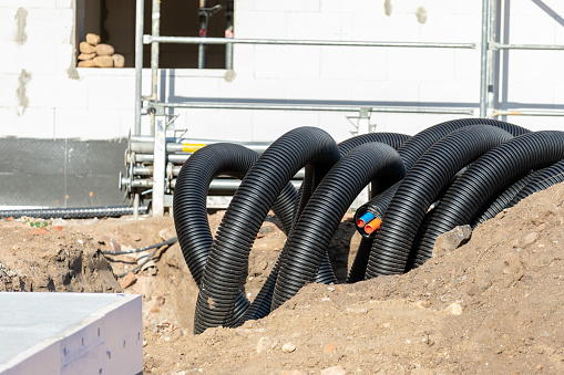 Black PVC flexible corrugated plastic insulation pipes tubing of electrical cables wire at undeground installation. New modern building construction site with engineering pipeline drainage technology.