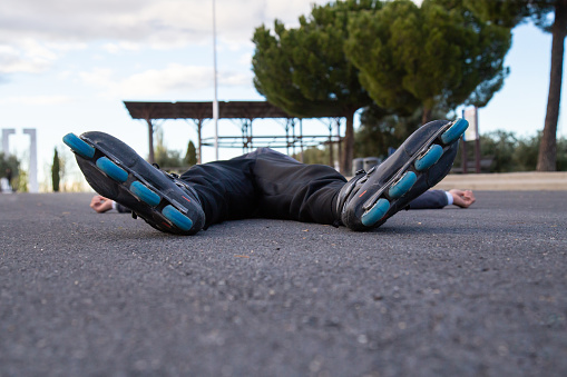 Tired male with roller skates lying on road