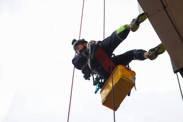 istock Man industry mountaineer worker in uniform and helmet hanging on wall working on building, bottom view. Access laborer high-rise rope danger works. Industrial urban works concept. Copy ad text space 1648865330