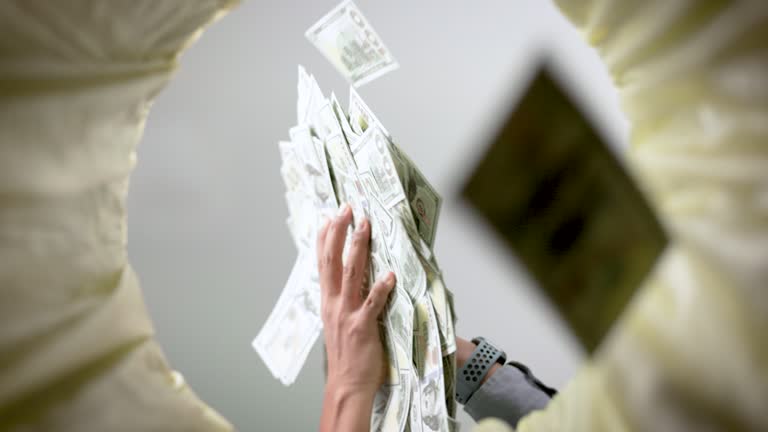 Super slow motion shot of dollar bills falling into wastepaper basket.