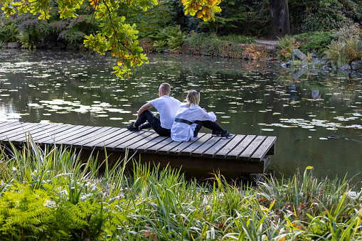 Wroclaw, Poland - September 30, 2021: Japanese Garden in Szczytnicki Park, exotic plants. A couple of young people sitting on a wooden pier