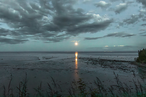 The full moon is rising at Baie Ste-Catherine beach at low tide. The St. Lawrence River at the mouth of the Duck River.