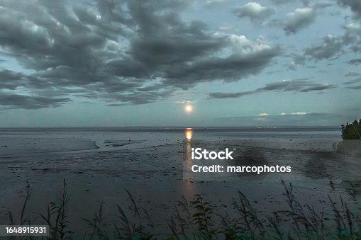 istock Full moon rising on St-Lawrence river. Baie Ste-Catherine beach at low tide. 1648915931