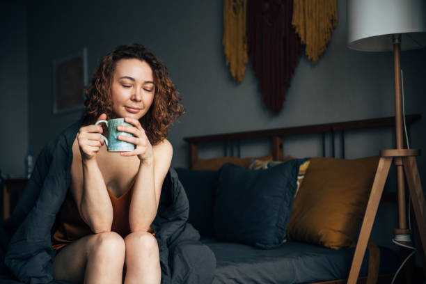 istock Girl drinking a relaxing drink with CBD tincture before going to bed, sitting in bed 1648917511