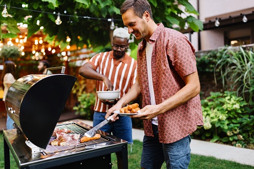 Two male friends are preparing a barbecue in the backyard