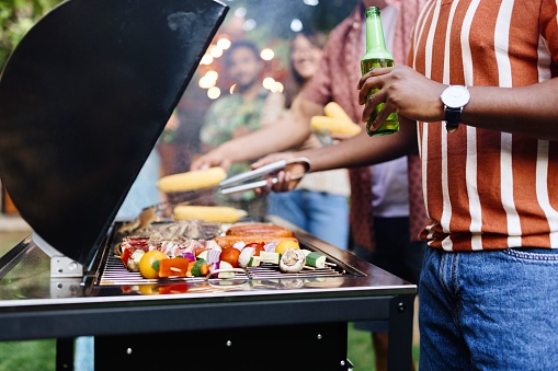 Close-up picture of people preparing barbecue on a grill