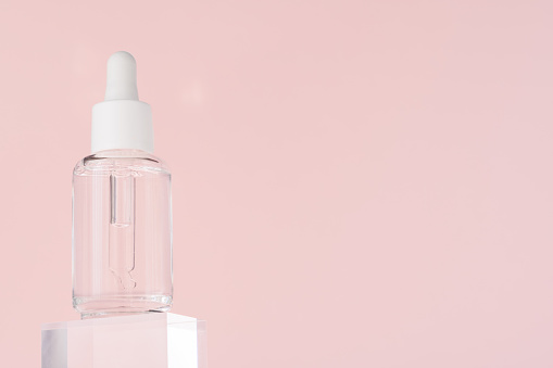 Hyaluronic acid oil, serum with collagen and peptides skin care product on transparent acrylic cube. Cosmetic liquid mockup in transparent bottle. Mock up packaging, cosmetics design branding
