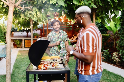 Men talking while preparing a barbecue in the backyard