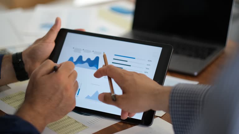 two businessmen discussing graphical data on tablet screen