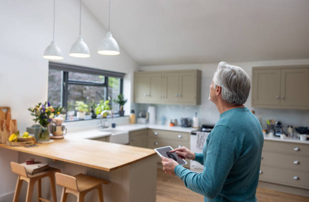 Senior man controlling the lights in his house using an automated system Senior man controlling the lights in his house using an automated system - smart home concepts home automation stock pictures, royalty-free photos & images