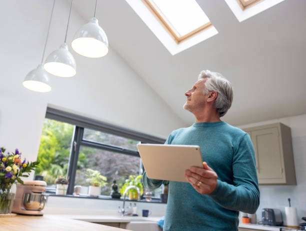 Senior man controlling the lights in his smart home using a digital tablet