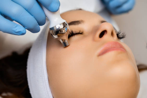 istock Spa worker makes lady face massage with appliance in office 1649044846