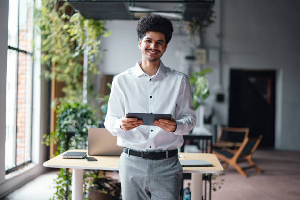 istock A Happy Handsome Businessman Looking At Camera While Working On His Tablet 1649044985