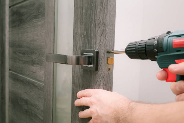 istock Handyman Fitting A New Door Using A Screwdriver At Home. Carpenter at lock installation with electric drill into interior wood door 1649054404