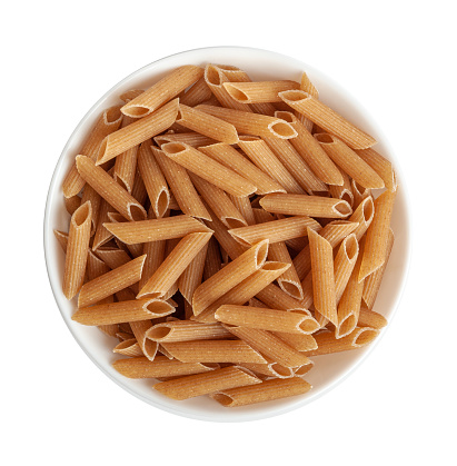 Raw Brown Pasta Isolated, Wholegrain Penne Pile in Bowl, Dry Whole Grain Noodle, Raw Spelt Macaroni, Healthy Italy Food, Organic Meal, Wholewheat Pasta on White Background