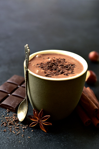Spicy hot chocolate with ingredients for making on a black slate, stone or concrete background.