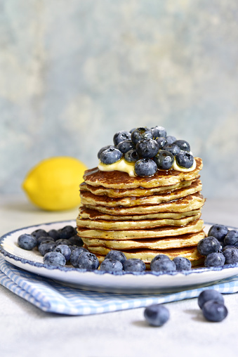 Lemon pancakes with fresh blueberry and whipped cream on a light background