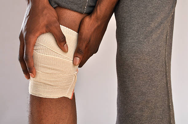 knie schmerzen - human knee physical injury bandage muscular build stock-fotos und bilder