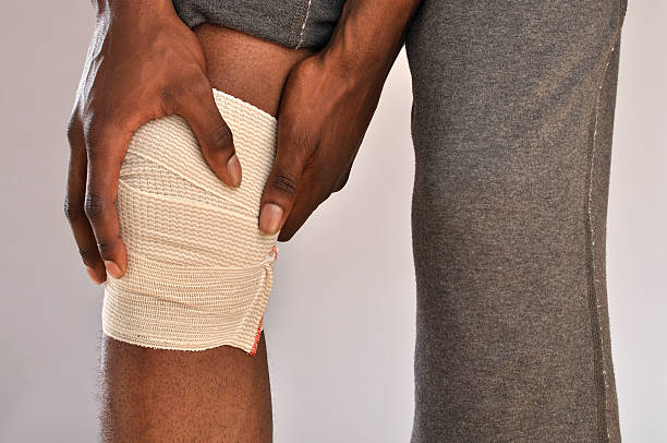 dolore al ginocchio - human knee physical injury bandage muscular build foto e immagini stock