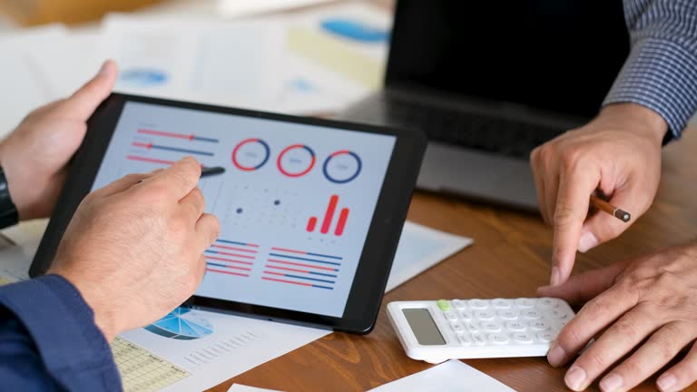 two businessmen discussing graphical data on tablet screen