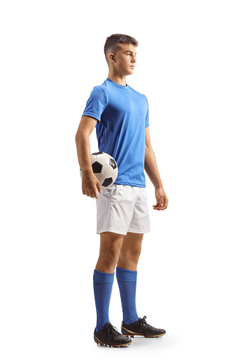 Football player in a blue top and white shorts holding a ball isolated on white background