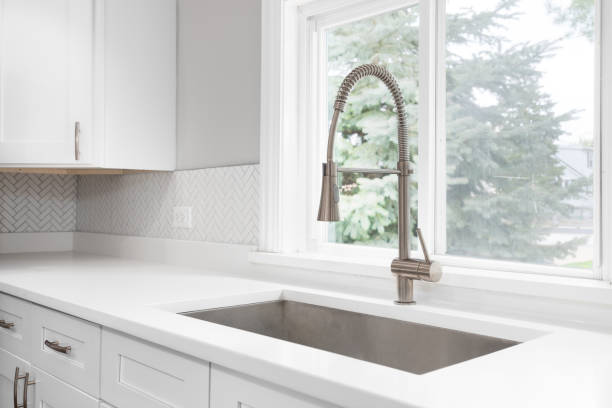 istock A kitchen faucet detail with white cabinets and herringbone tile backsplash. 1649121054