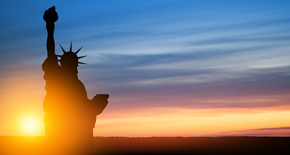 Statue of Liberty on background of sunset sky. Close-up. Greeting card for Independence Day. USA celebration.