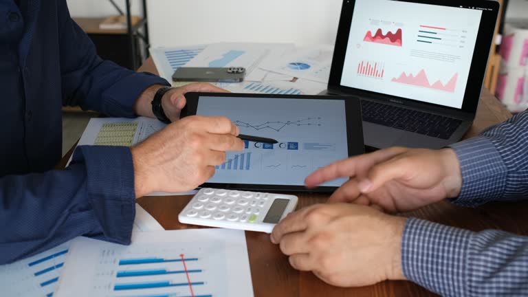 two businessmen discussing graphical data on tablet screen