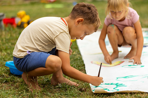 Children and one modern father playing games and painting in the backyard