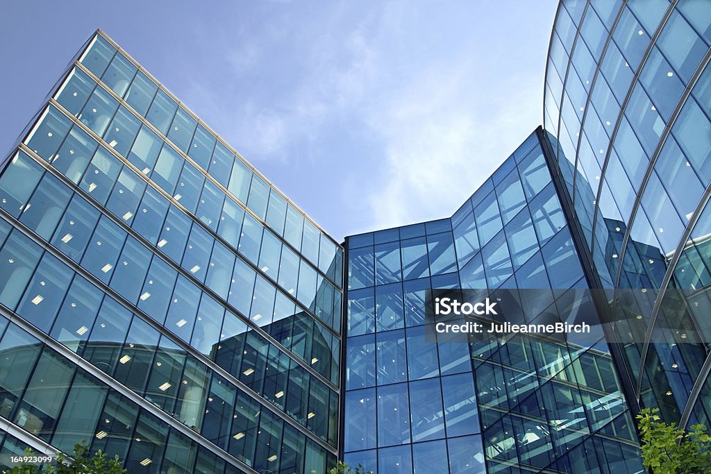 Low angle view of the exterior of a corporate glass building Turquoise plate glass office building against a sunny blue sky Office Park Stock Photo