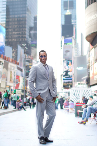 Young businessman smiling, standing in Times Square, NYC. Soft focus.