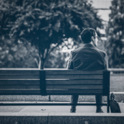 A man sits on a bench as time passes him by.