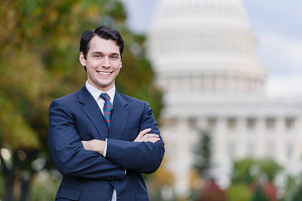 I Know How To Fix Washington A young politician, staffer, or lobbyist holds with his arms folded, with a confident smile. The United States Capitol building is in the background. politician stock pictures, royalty-free photos & images