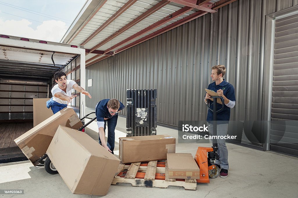 Careless Dock Workers Dropping Delivery Boxes While Loading Truck Workers loading a delivery truck. Falling Stock Photo