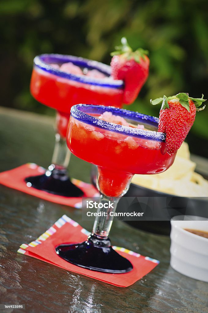 Frozen Margaritas Two frozen Strawberry margaritas with chips and salsa in the background. Frozen Drink Stock Photo