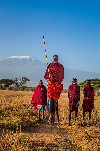 African warrior from Maasai tribe performing a traditional jumping dance, central Kenya, Africa - Mount Kilimanjaro on the background. Maasai tribe inhabiting southern Kenya and northern Tanzania, and they are related to the Samburu.
