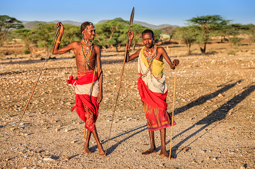African warriors from Samburu tribe standing on savanna and holding a spears, central Kenya. Samburu tribe is one of the biggest tribes of north-central Kenya, and they are related to the Maasai.