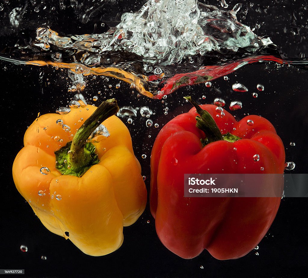 Pimenta Amarela e Vermelha, caindo na água em fundo preto - Foto de stock de Bolha - Estrutura física royalty-free