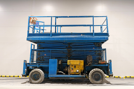 Hydraulic lifting platform on the construction site of an industrial building. A scissor elevator inside a warehouse