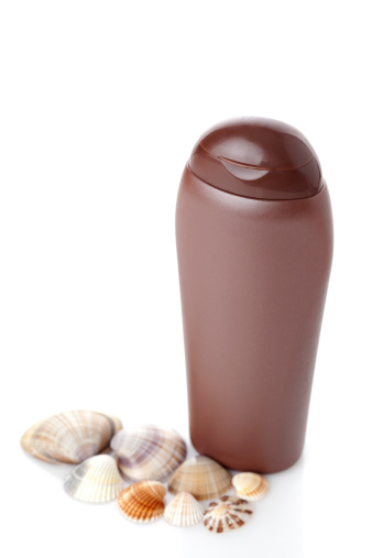 Suntan Lotion Bottle and shells isolated on white