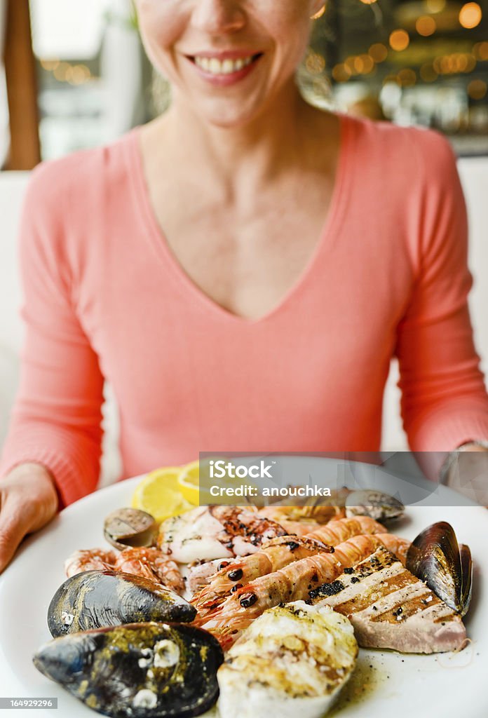 Feliz sonriente mujer madura con plato de pescados y mariscos a la parrilla - Foto de stock de Comer libre de derechos