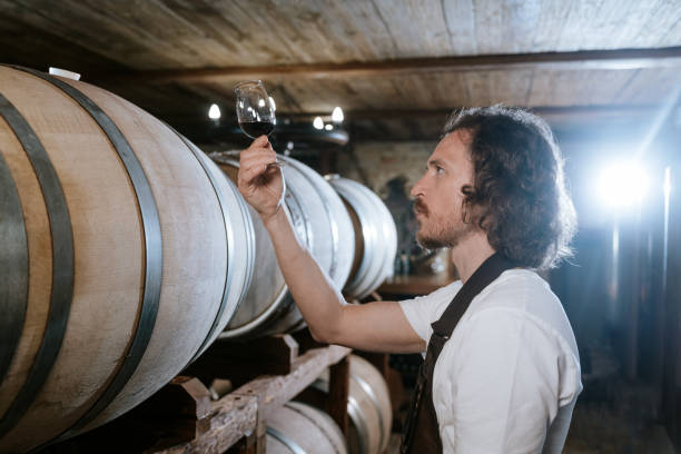 istock Winemaker tasting wine in a cellar with wooden barrels 1649296737