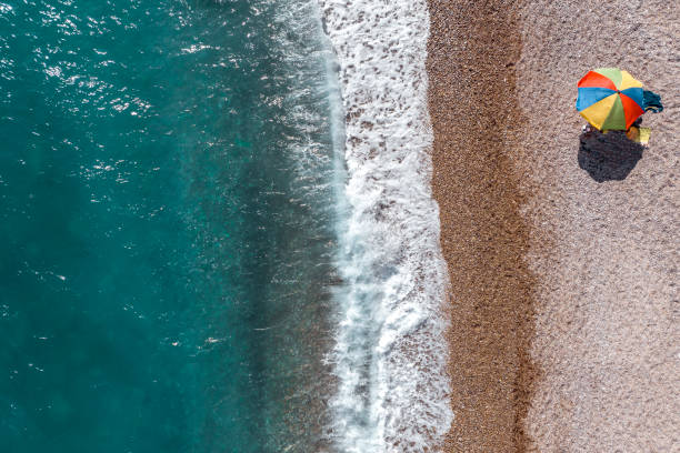 istock Emerald water, waves, beach and umbrella seen directly from above 1649297870