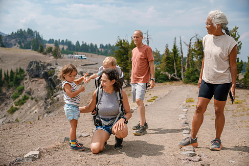 A multiracial multi-generation family cheerfully talks while on a fun and relaxing hike near Crater Lake in Oregon.