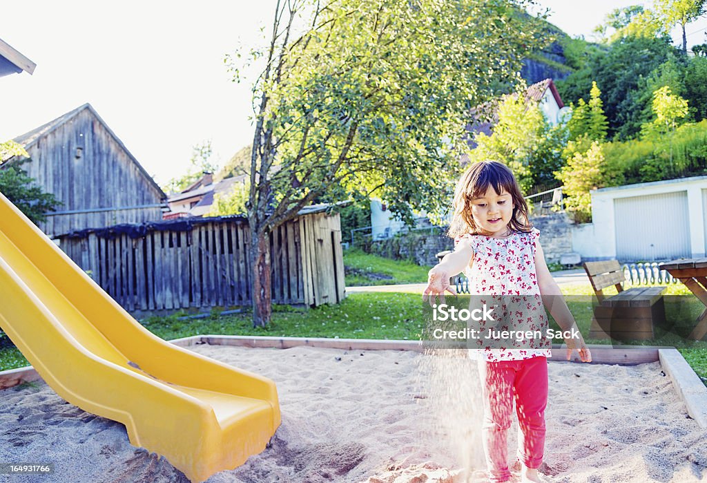 Playing with sand 3 years old girl playing in a sandbox in rural Germany. Sandbox Stock Photo