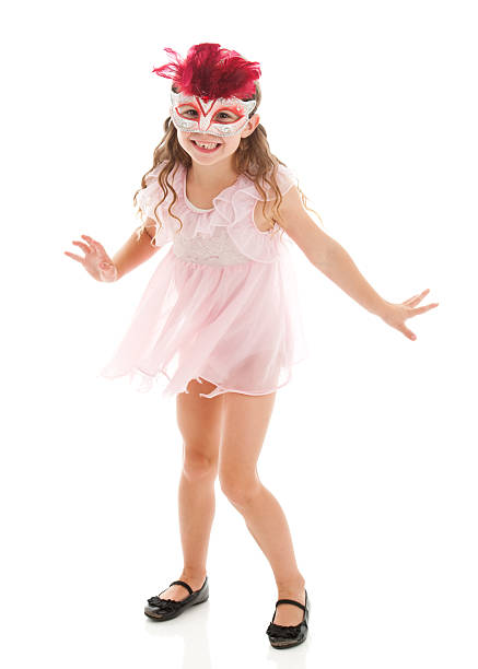 little girl disguised in a blue witch costume, in front of a pink background, holding her hat and smiling