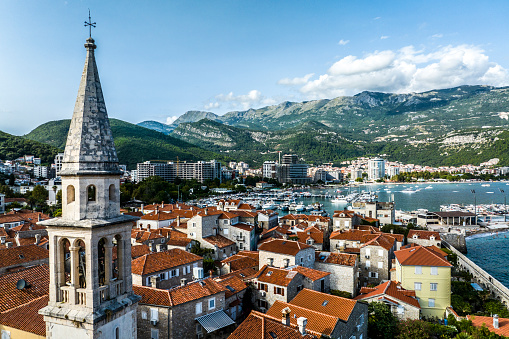 A landmark bell tower of the ancient basilica seen in the old town Budva, Montenegro and captured with a drone during one late summer afternoon making a postcard scenery.