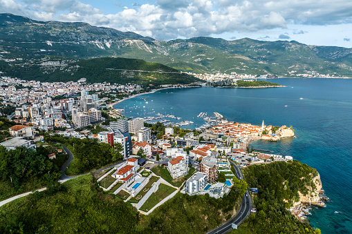 Amazing scenery of the city of Budva in Montenegro surrounded with beautiful mountains and bleu waters of the Adriatic sea seen from a drone perspective during one late summer afternoon.