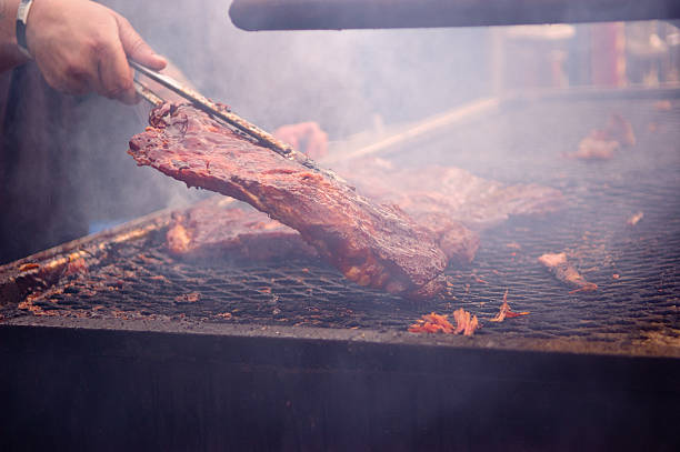 istock Vendor turning meat on smokey grill 164942255